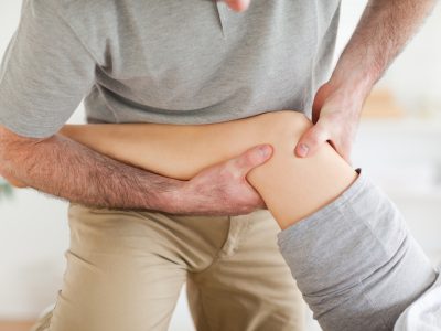 Chiropractor massaging a patient's knee in a room